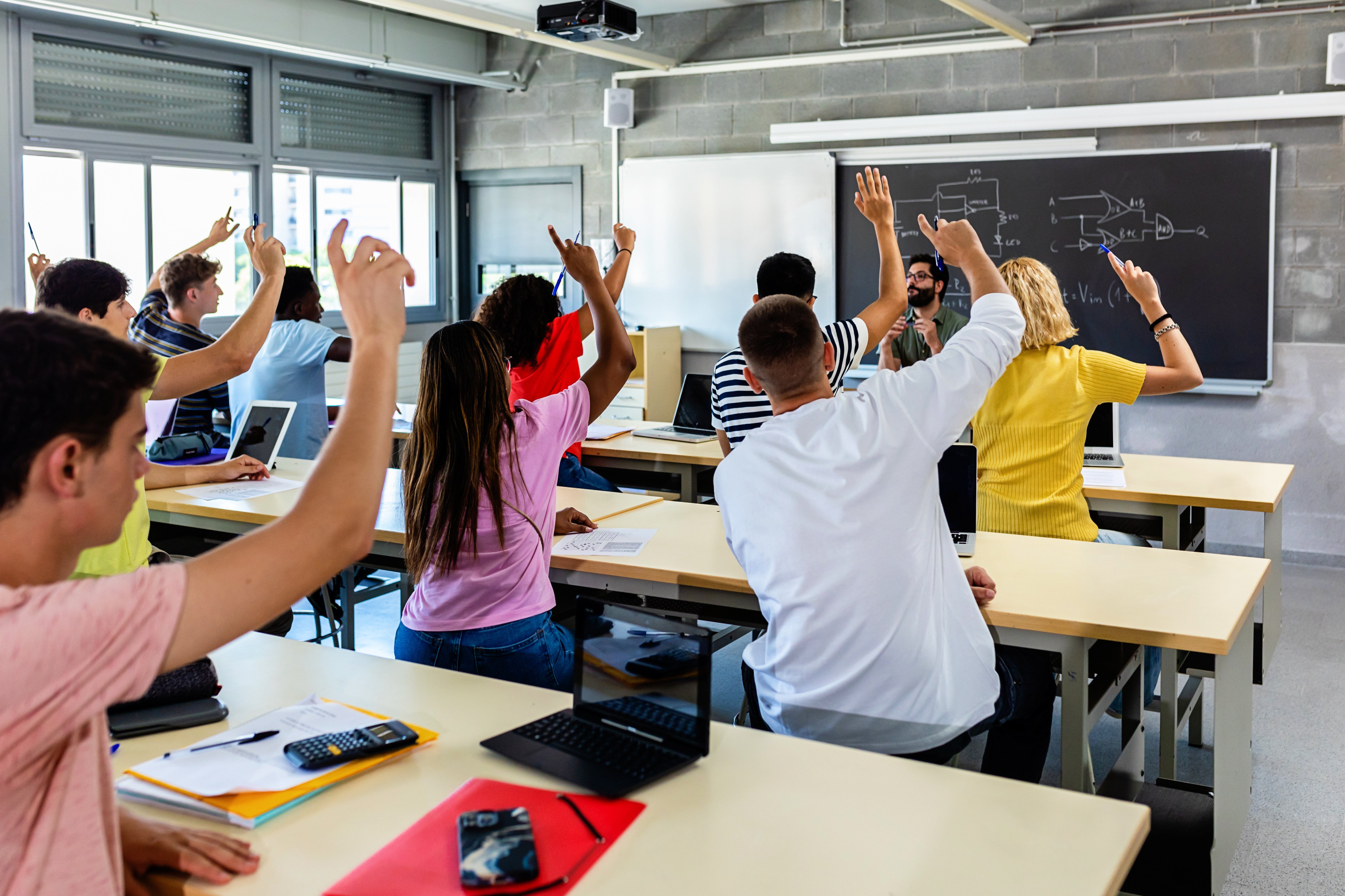 Students raising their hands in a high school classroom